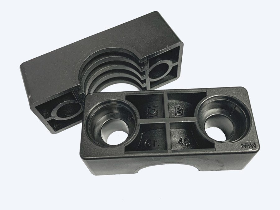 Polyamide STAUFF clamp body in black, shown open with the grooved bore and a matching polyamide plate